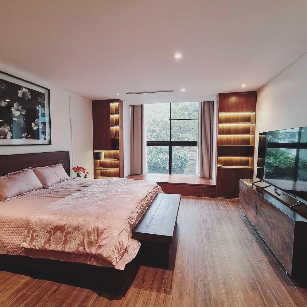 Phòng ngủ master được thi công toàn bộ bằng gỗ công nghiệp có bục lớn cạnh cửa sổ kính lớn