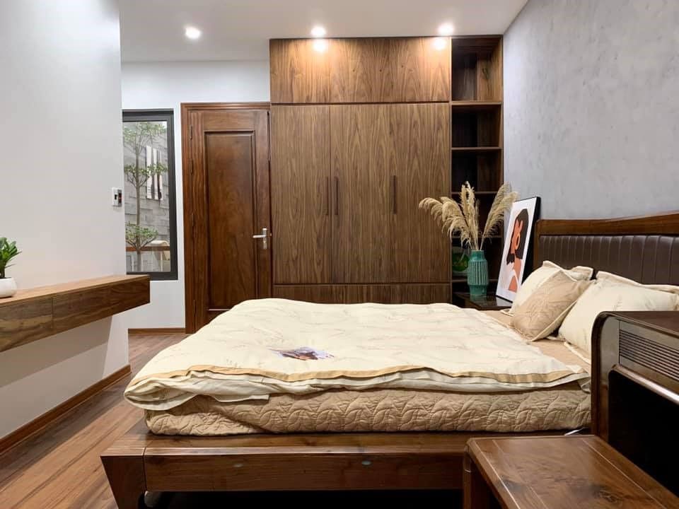 Phòng ngủ hiện đại sử dụng nội thất tông màu gỗ trầm trên nền xám tăng cảm giác ấm áp, hệ tủ quần áo cao đụng trần tích hợp cùng kệ trang trí