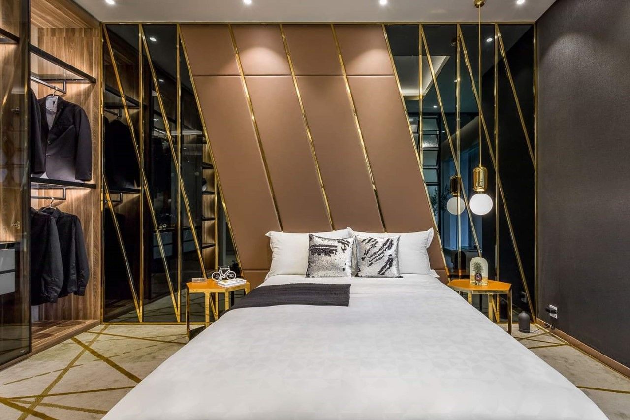 Phòng ngủ thiết kế theo phong cách sang trọng với điểm nhấn là vách đầu giường ốp nệm da cùng kính đen chạy chỉ vàng khiến căn phòng trở nên đẳng cấp hơn